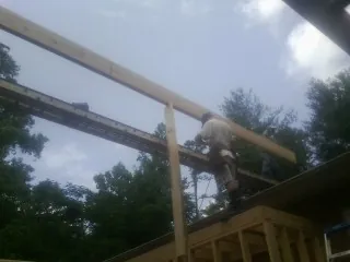 Carpenter setting a ridge beam over a new addition frame — Ice Dam Removal by Roofing Brothers in Elbert