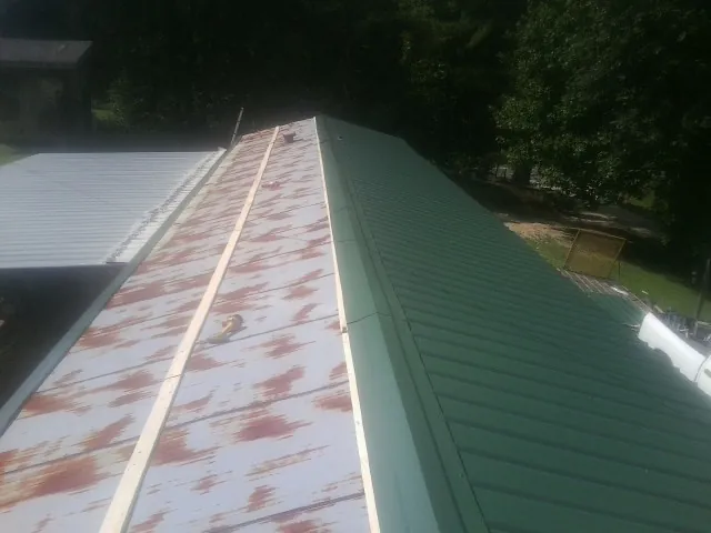 Old rusted panels beside newly installed green metal roofing — Wind Damage Roof Repair by Roofing Brothers in Elbert