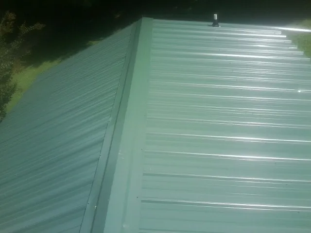 New green metal panels meeting at the ridge of a roof — Flat Roof Repair work by our crew in Elbert