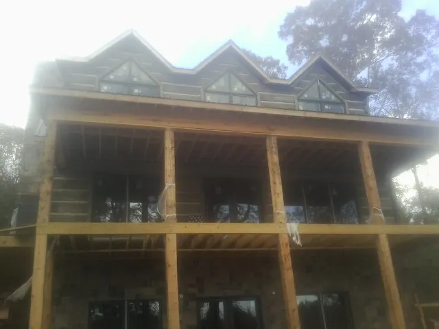 Dormers and porch framing on a large log home under construction — Roof Coating work by our crew in Elbert