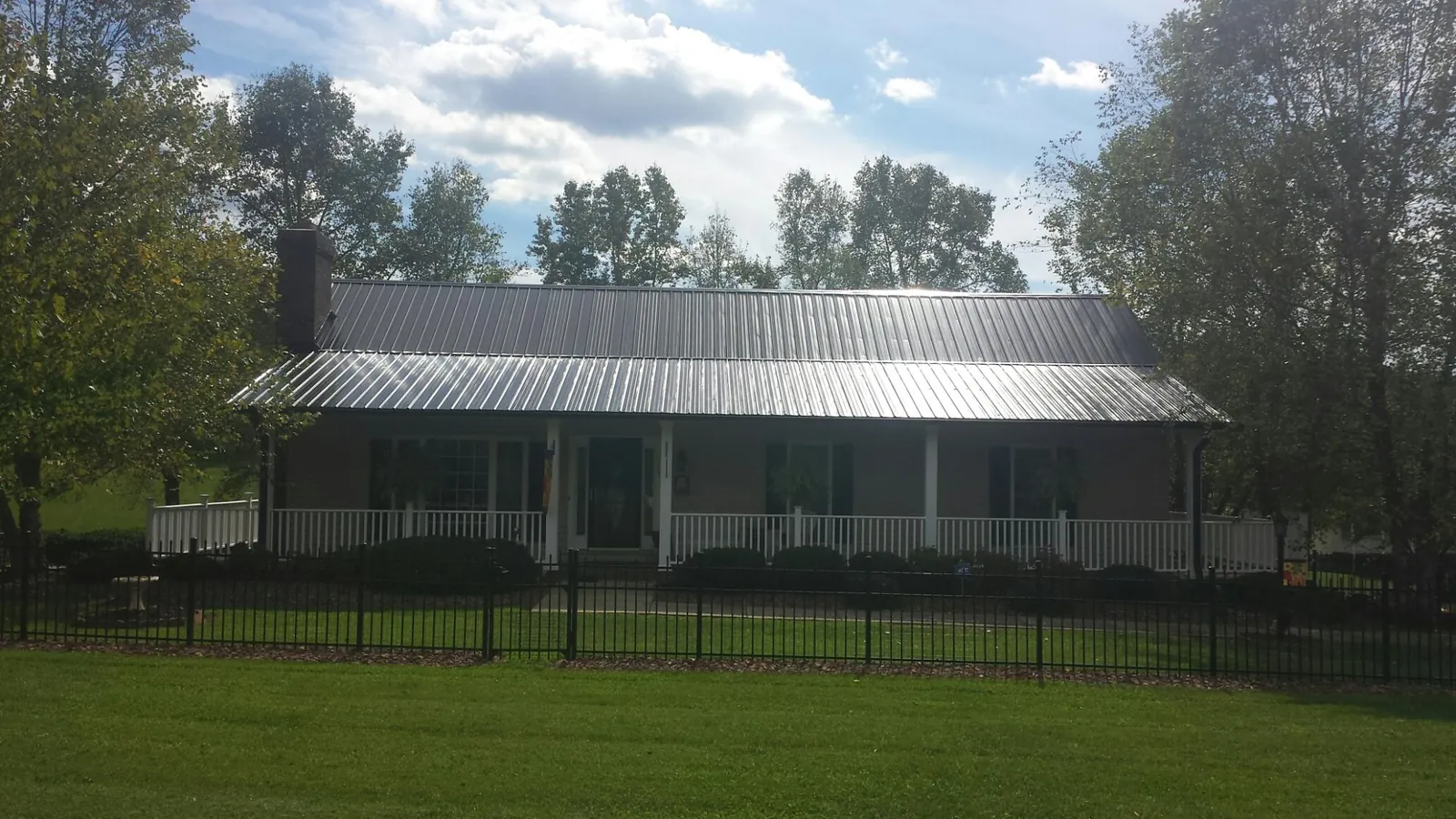 Gray metal roof on a brick ranch with a full width front porch — Gutter Guard Installation work by our crew in Elbert