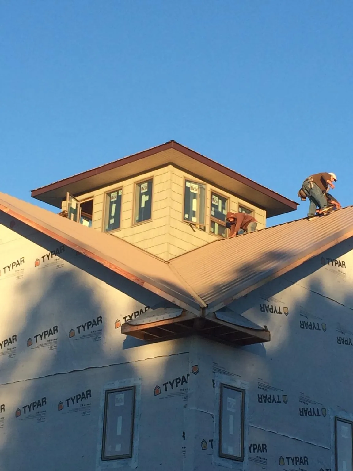 Roofers working around a rooftop cupola on a new metal roof at sunset — Roof Waterproofing in Elbert by Roofing Brothers